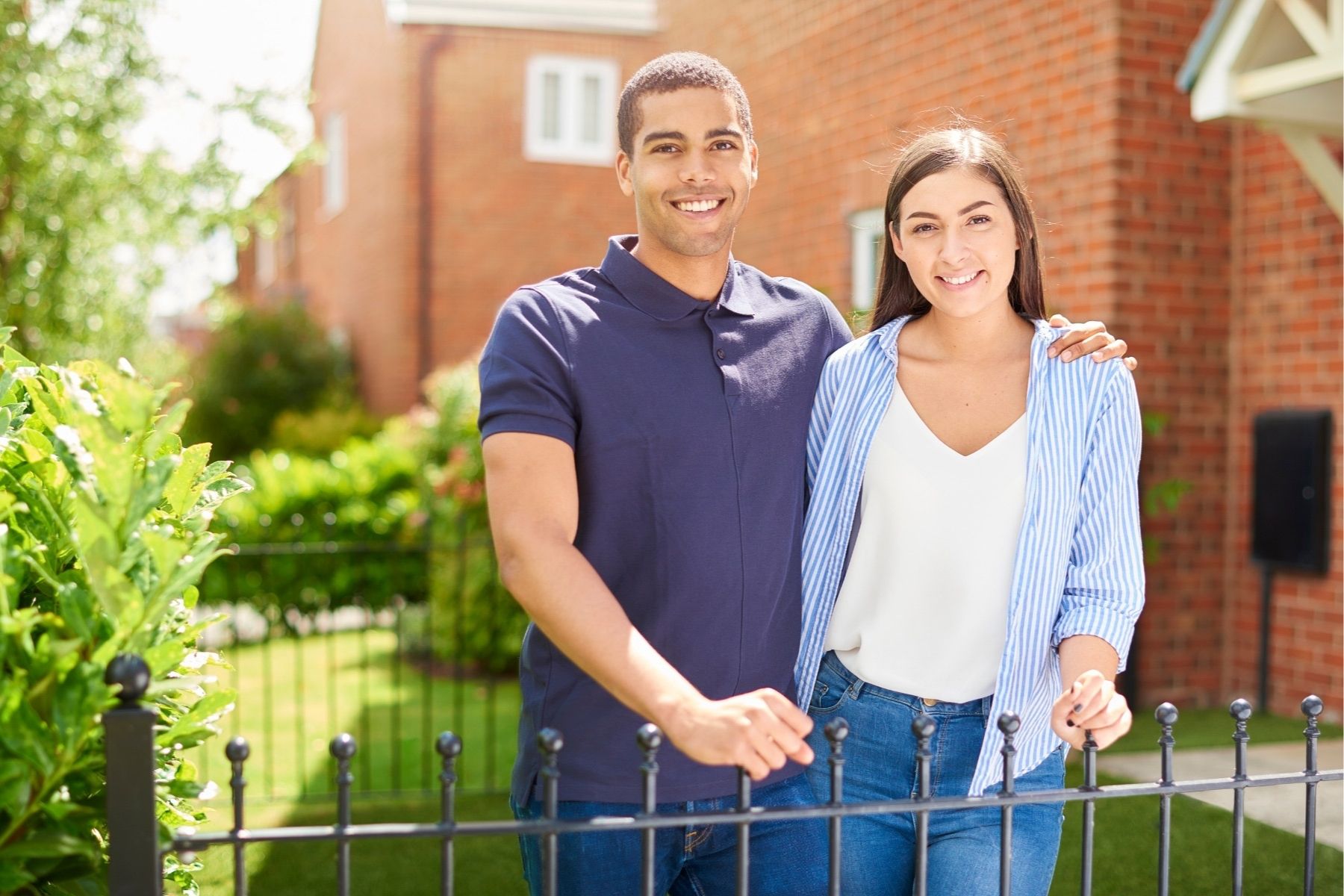 Young couple standing in front of their brand new home